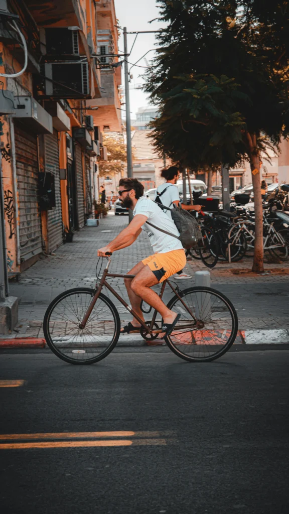 homem pedalando em ambiente urbano, postura relaxada, roupa casual